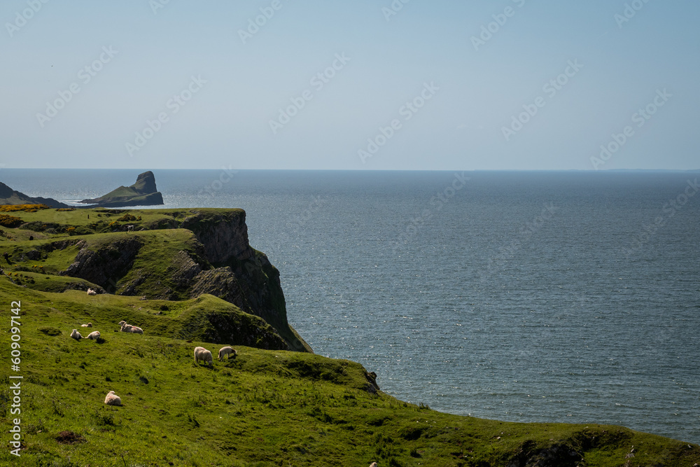 View from the top of worms head looking over the cliff to the sea water on a sunny summer day in South Wales UK on the Gower peninsula. Rugged natural beauty from British outdoor landscape View from the top of worms head looking over the cliff to the sea water on a sunny summer day in South Wales UK on the Gower peninsula. Rugged natural beauty from British outdoor landscape