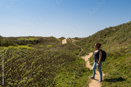 Active outdoor lifestyle in the British coastal countryside. young lady embraces the great outdoors in the Gower peninsular trekking over grassy sand dunes to get to Rhossili beach on a sunny day photo