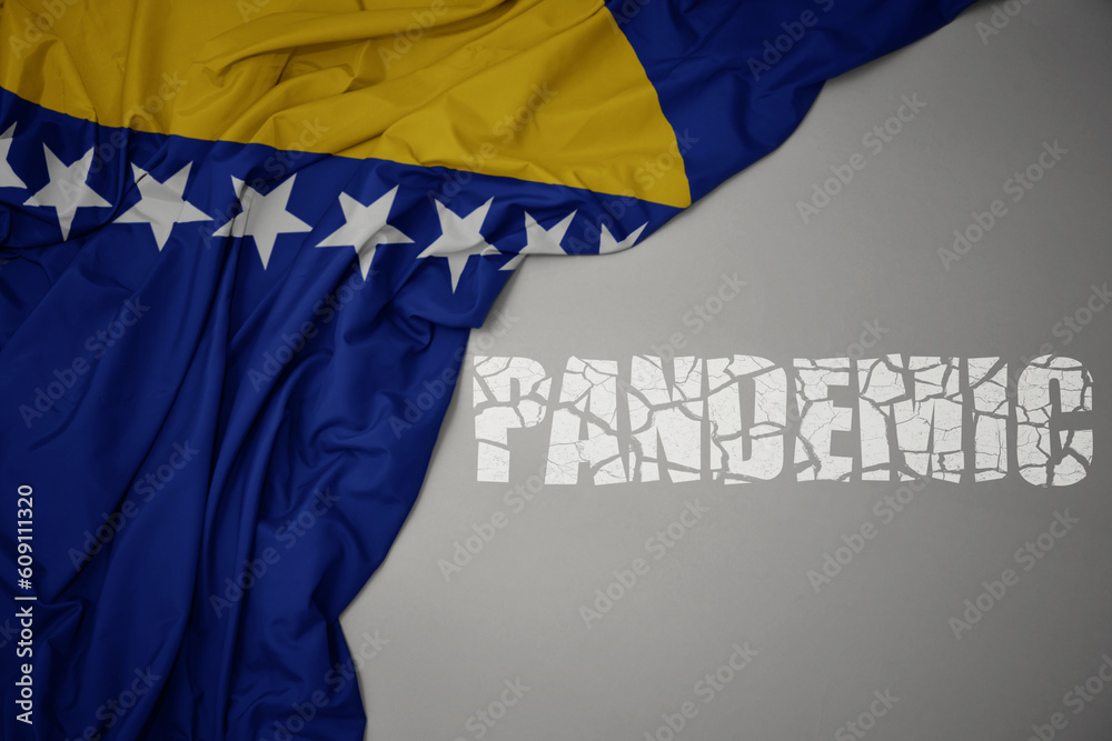 waving colorful national flag of bosnia and herzegovina on a gray background with broken text pandemic. concept.
