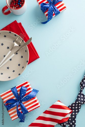 Fotografia, Obraz Commemorate America's independence with stunning table display! Vertical top view collection of patriotic elements: plate, cup, napkin, tie, gift boxes on pastel blue backdrop