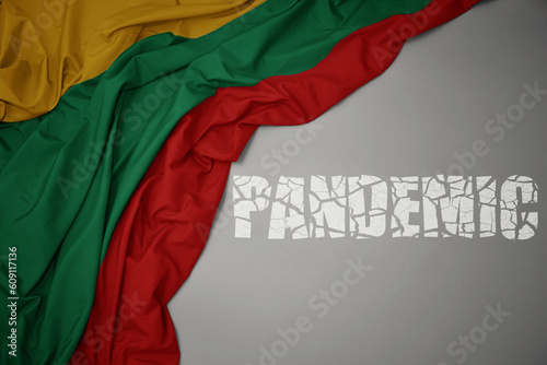 waving colorful national flag of lithuania on a gray background with broken text pandemic. concept.