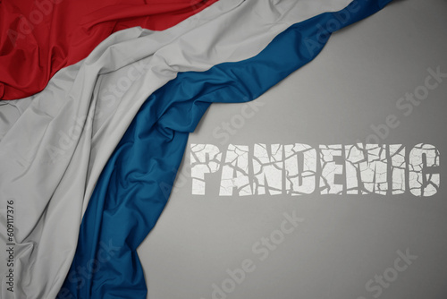 waving colorful national flag of luxembourg on a gray background with broken text pandemic. concept.