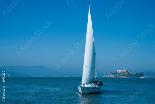 A sailboat cruises on San Francisco Bay as Alcatraz prison looms in the background.