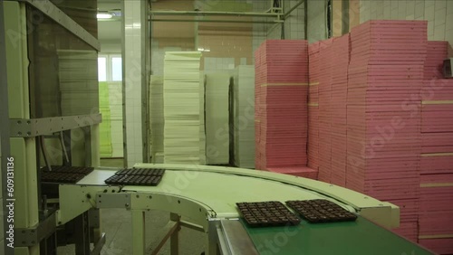 static medium shot of chocolates in a package on a conveyor line, 90 degree angle turn