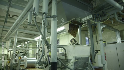 panning down wide shot of a clumped mass of nuts and jelly falling from a mixer onto a press line in a chocolate factory photo