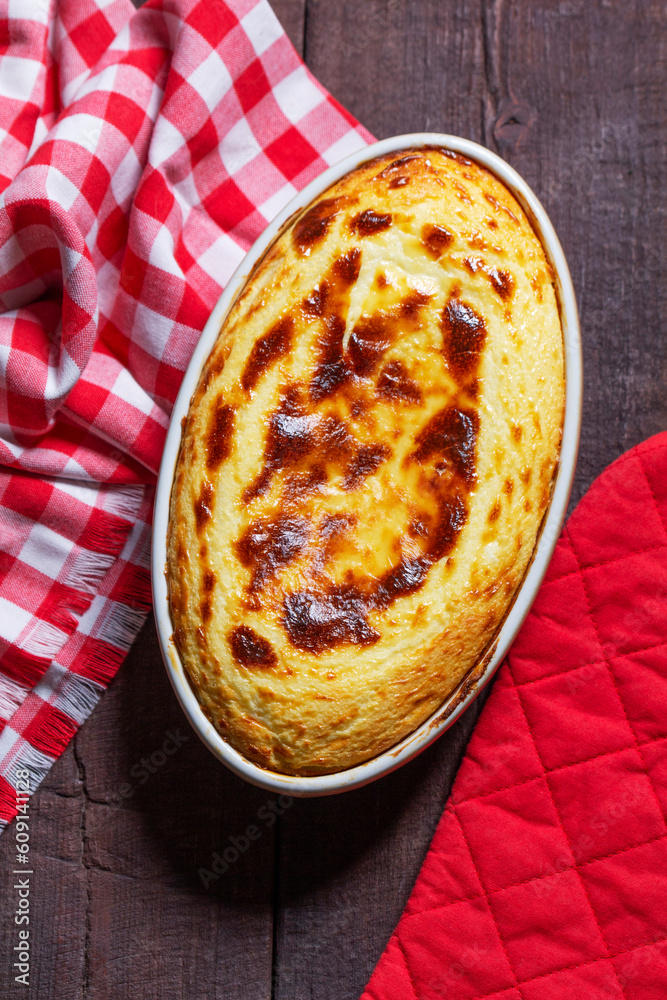 Cottage cheese casserole in an oval ceramic form on a wooden background. Rustic style.