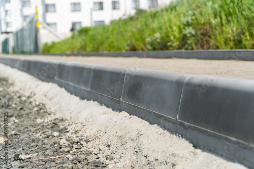 Construction of a pedestrian path. Paving of pedestrian paths on city streets. Road curbs and sidewalks. New curbs close up. Curbs detail. Soft focus photo