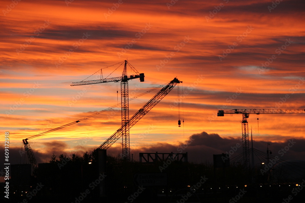 Sunset and construction cranes over Glasgow skyline.
