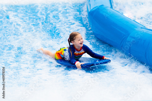 Canvas Print Little girl surfing in beach wave simulator
