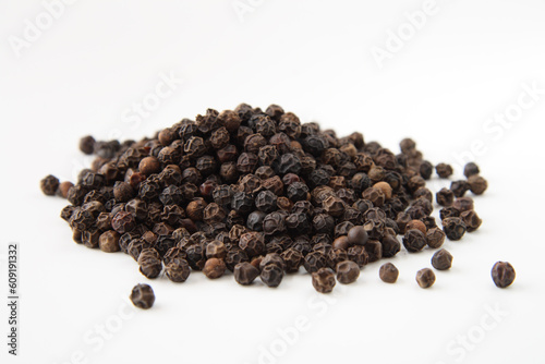 Whole black pepper, isolated on white. Shallow depth of field, focused on the centre of the pile.