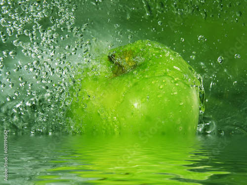 Water drops falling onto a green apple photo