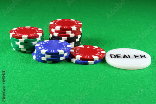 Fotografie Poker chips with a dealers chip on green baize