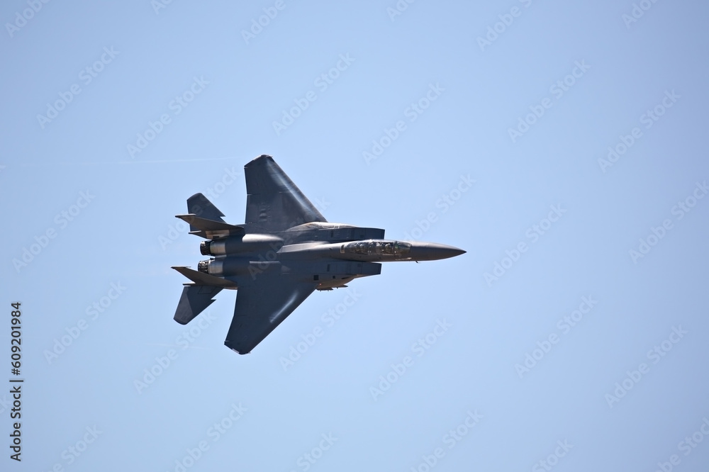 F-15 strike eagle in flight against blue sky, banking hard right F-15 strike eagle in flight against blue sky, banking hard right