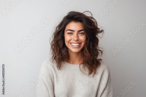 Portrait of a happy young woman looking at camera over grey background