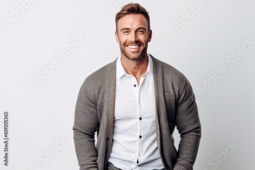 Medium shot portrait photography of a grinning man in his 30s that is wearing a chic cardigan against a white background . Generative AI