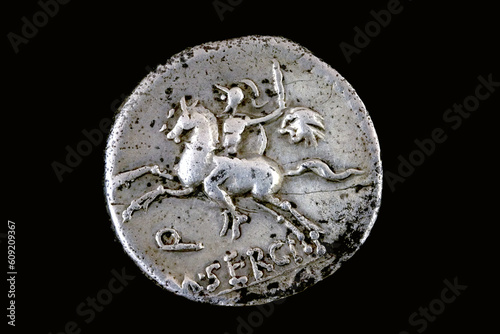 Reverse of a Roman republican denarius of M. Sergius Silus. 116 BC.  A horseman is galloping to the left while holding a sword and the head of a barbarian in his left hand. Q M SERGI is below and SILV photo
