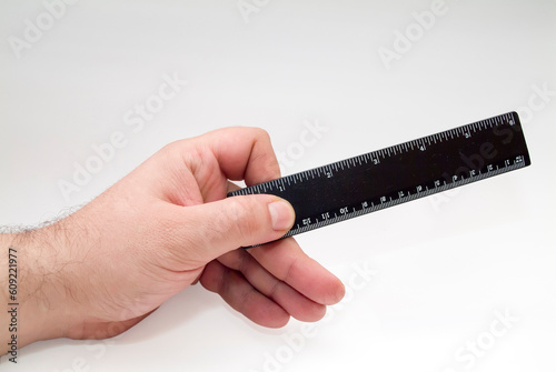 hand with black ruler over white background