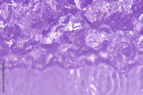 Purple water with ripples on the surface. Defocus blurred transparent pink colored clear calm water surface texture with splashes and bubbles. Water waves with shining pattern texture background.