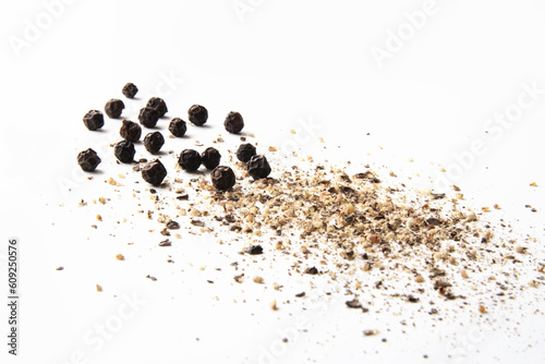 whole and ground black pepper on white