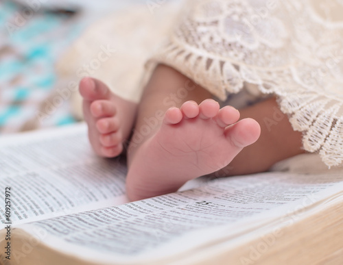 Close up shot of the soft tender legs of a Nigerian new born baby child placed on an open Bible book