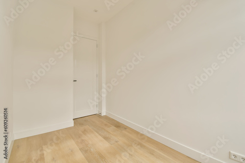 an empty room with white walls and wood flooring on the right, there is a door that leads to another room