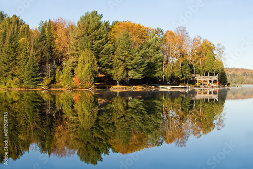 Boat docks and fall trees, along the shore of a clear blue lake.