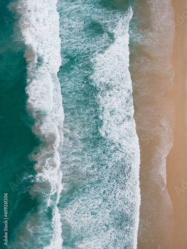 Simple top down drone view of waves coming ashore a sandy beach in symmetrical lines from left to right. Good for background or wallpaper. 