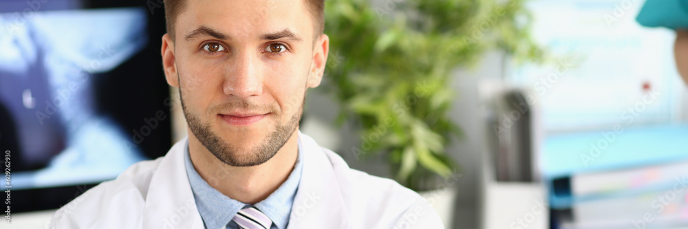 Fototapeta premium Portrait of young handsome male doctor in clinic. Medical services and insurance concept