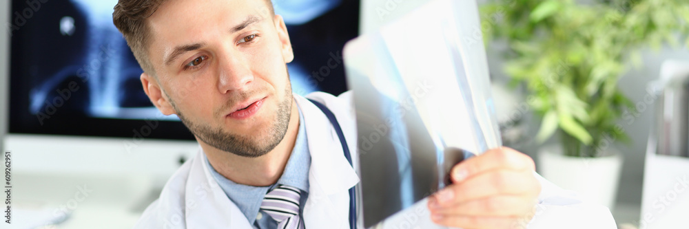 Fototapeta premium Male doctor examines x-ray of leg and arm in clinic. Medical diagnosis of fractures concept