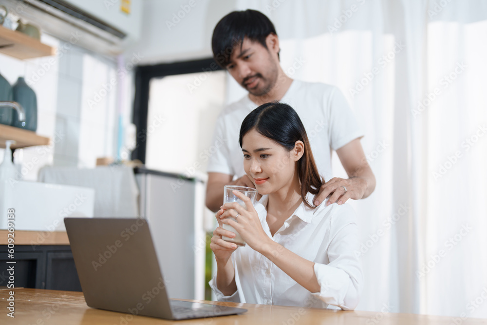 Young married couple showing happy smiling faces and using computers and notebooks to calculate household income and expenses while relaxing at home. Young married couple showing happy smiling faces and using computers and notebooks to calculate household income and expenses while relaxing at home.