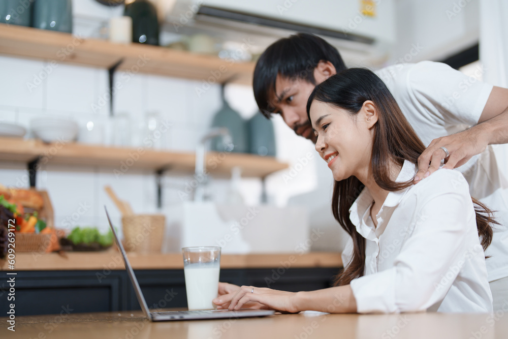 Young married couple showing happy smiling faces and using computers and notebooks to calculate household income and expenses while relaxing at home. Young married couple showing happy smiling faces and using computers and notebooks to calculate household income and expenses while relaxing at home.