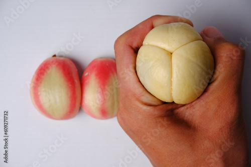 two slightly reddish zalacca or Salacca zalacca and slightly white off-white fruits which are held and have been peeled