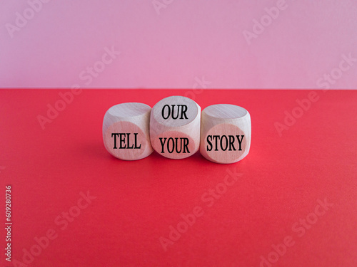 Tell our or your story. Turned wooden cubes and changed words tell our story to tell your story. Beautiful red table, pink background, copy space. Business, storytelling and our or your story concept.