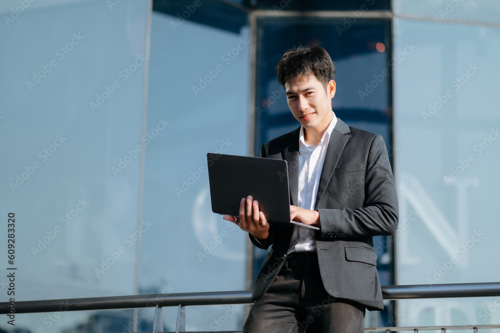 Young Asian business man working at outside business center with laptop, tablet, smartphone and taking notes on the paper. Young Asian business man working at outside business center with laptop, tablet, smartphone and taking notes on the paper.