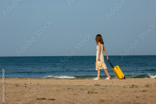 girl in a dress with a suitcase on the beach