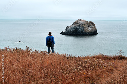 person hiking and walking toward the ocean view of the coast