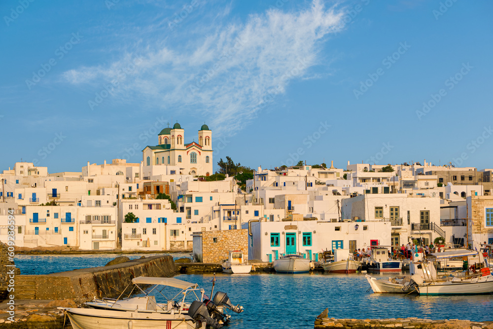 Greek whitewashed houses and church by harbour watersfront on sunny