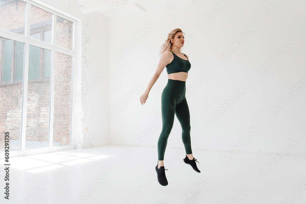 Fototapeta premium Active strong woman with blond hair jumping at white hall