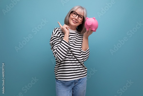 Fotografía pleasant middle-aged woman 50 years old holding a piggy bank with savings on a b