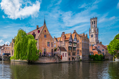 Historic buildings along a canal and the Belfort tower in Bruges, Belgium