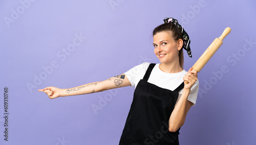 Cooker Slovak woman isolated on purple background pointing finger to the side and presenting a product