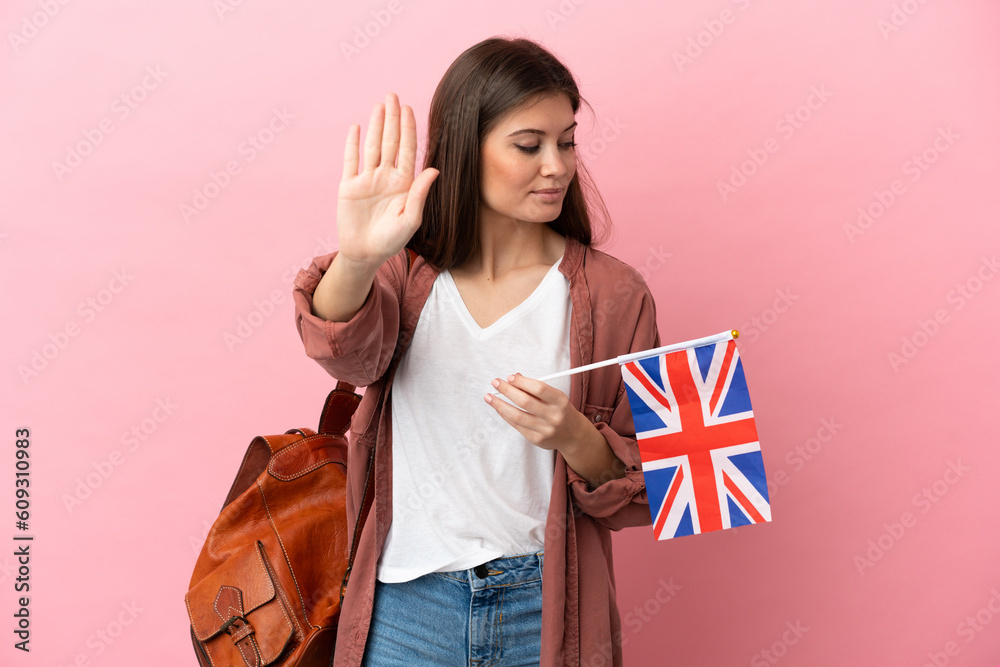 Young caucasian woman holding an United Kingdom flag isolated on pink background making stop gesture and disappointed Young caucasian woman holding an United Kingdom flag isolated on pink background making stop gesture and disappointed