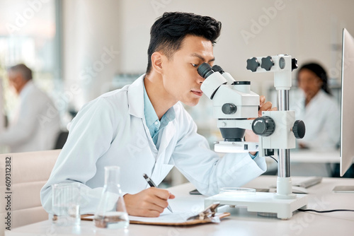 Science, notebook and microscope with an asian man doctor working in a lab for research or innovation. Healthcare, medical and writing with a male scientist working in a laboratory for analysis