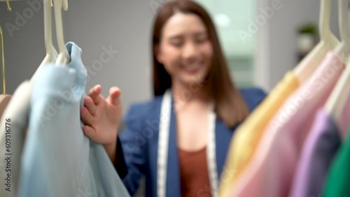 Beautiful attractive young Asia lady choosing her fashion outfit clothes in closet at home or store. Home wardrobe or clothing shop changing room.
