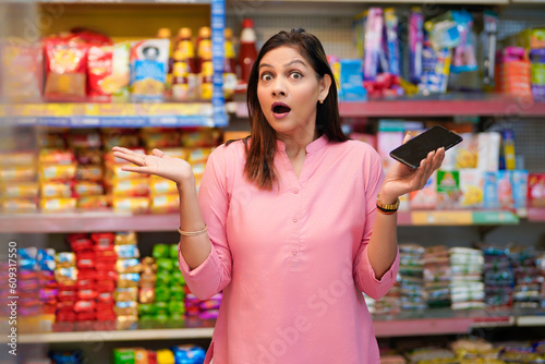 Indian woman giving shocking reaction after watching in smartphone at super shop
