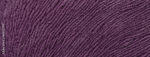 Texture of dark violet textile background from a soft wool material, macro. Fabric with purple wavy pattern.