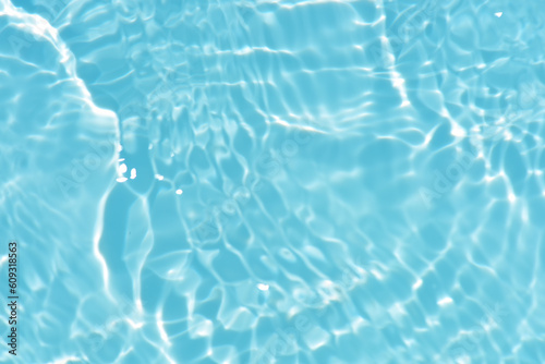 Blue water with ripples on the surface. Defocus blurred transparent blue colored clear calm water surface texture with splashes and bubbles. Water waves with shining pattern texture background.