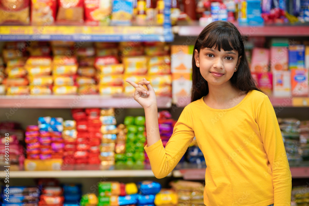Indian girl giving expression with hand at grocery shop.