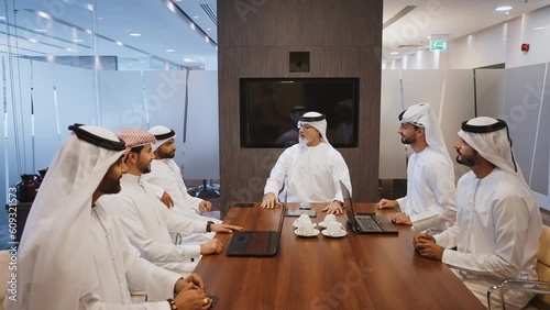 Business men from dubai working in an office. Business people of the emirates wearing the traditional white kandura outfit photo