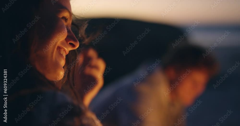 Happy, talking and a woman at a beach bonfire for conversation, holiday and summer happiness. Smile, laughing and a young girl at the ocean with a campfire and friends for the sunset and vacation